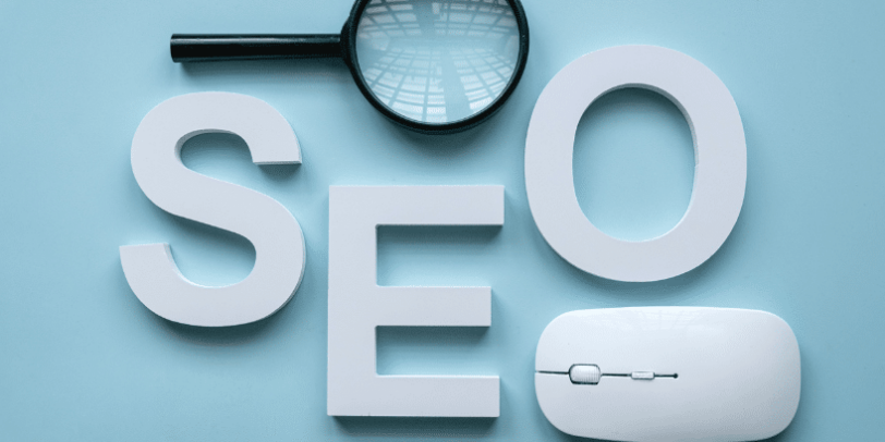 Loupes, lettres SEO, et souris sur fond bleu clair.